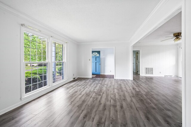 unfurnished living room with crown molding, baseboards, dark wood-type flooring, and visible vents