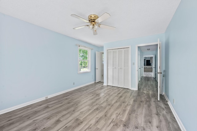 unfurnished bedroom featuring light wood-type flooring, baseboards, ceiling fan, and a closet