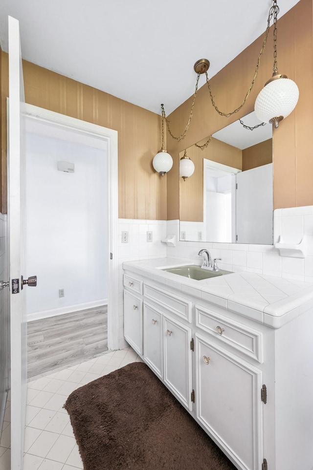 kitchen with tile countertops, white cabinets, a sink, light tile patterned floors, and hanging light fixtures