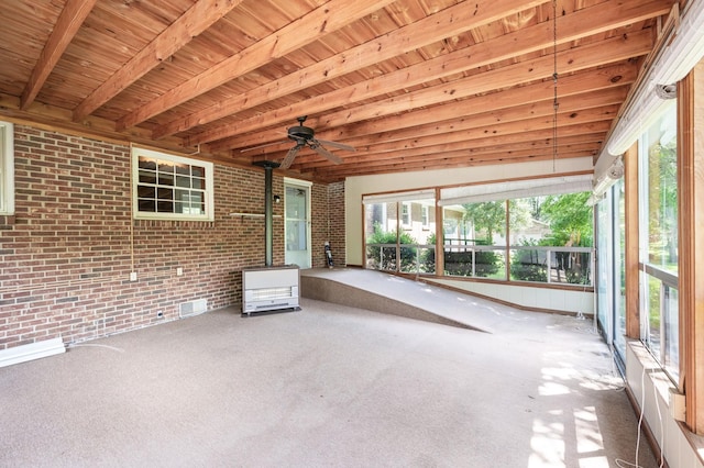unfurnished sunroom with visible vents, beam ceiling, and a wood stove
