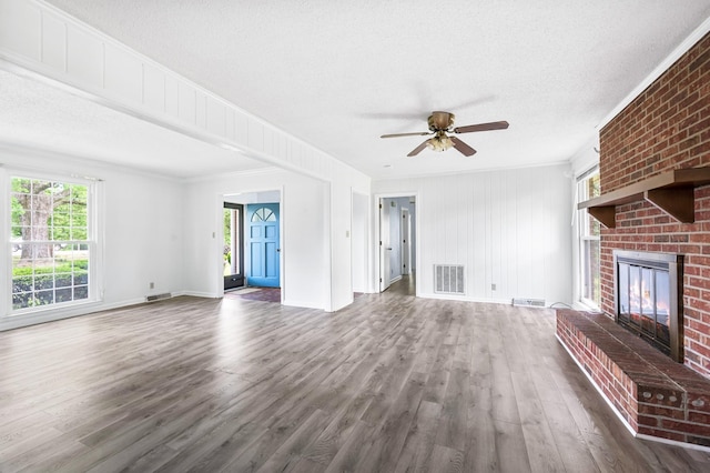 unfurnished living room featuring a healthy amount of sunlight, ceiling fan, wood finished floors, and visible vents