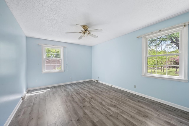 unfurnished room featuring baseboards, ceiling fan, a textured ceiling, and wood finished floors