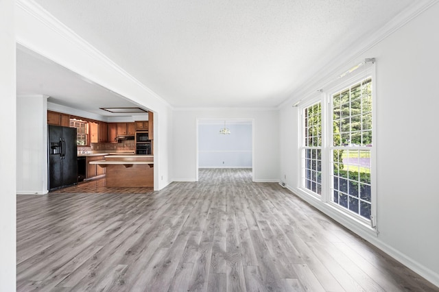 unfurnished living room featuring baseboards, ornamental molding, wood finished floors, and an inviting chandelier