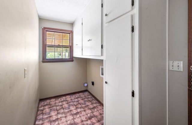 laundry room featuring cabinet space, a textured ceiling, baseboards, and washer hookup