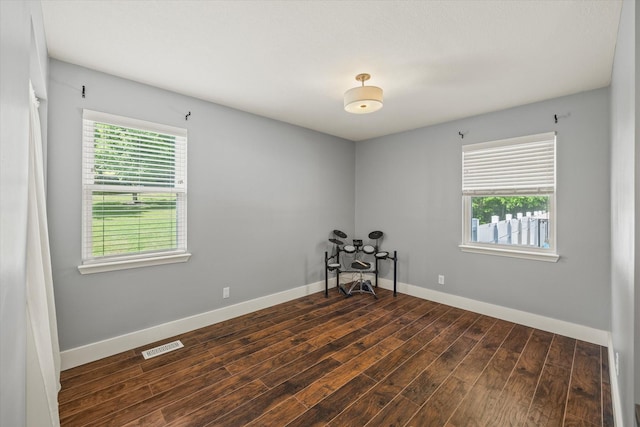 unfurnished room with baseboards, plenty of natural light, dark wood-style flooring, and visible vents