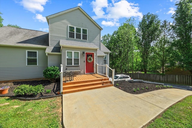 view of front of house featuring roof with shingles, fence, and a deck