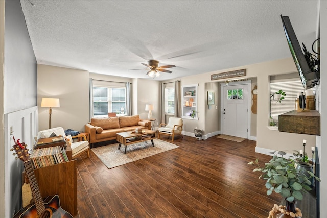 living area featuring baseboards, a textured ceiling, ceiling fan, and wood finished floors