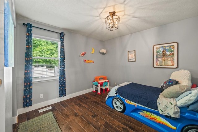 bedroom with baseboards, wood finished floors, and visible vents
