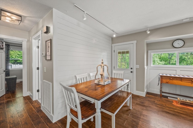 dining space featuring track lighting, visible vents, baseboards, plenty of natural light, and dark wood-type flooring