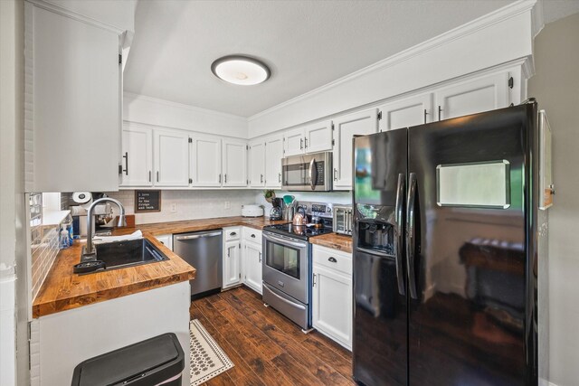 kitchen with ornamental molding, wooden counters, white cabinetry, a sink, and appliances with stainless steel finishes
