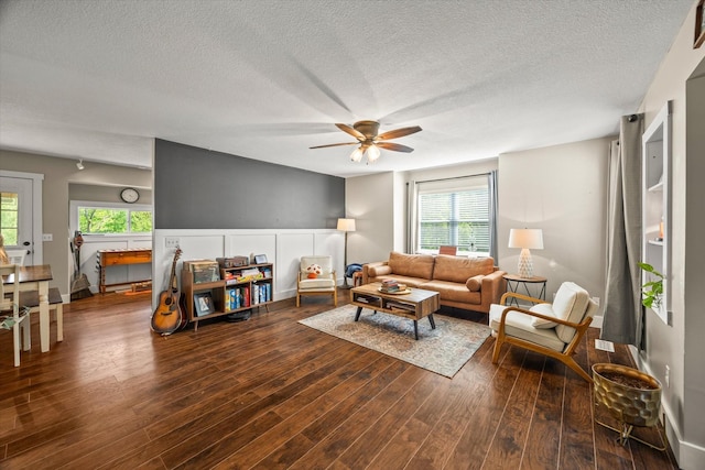 living area featuring dark wood-style flooring, a textured ceiling, ceiling fan, and a wealth of natural light