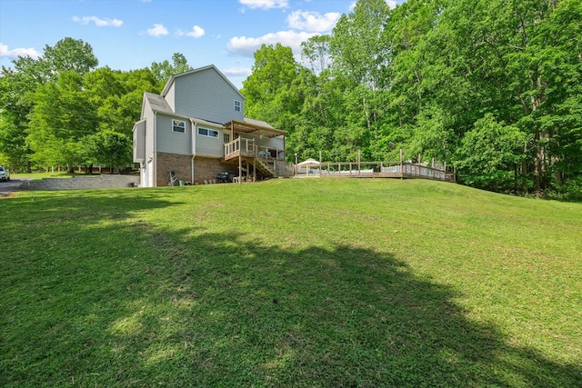 view of yard featuring stairway, a view of trees, a wooden deck, and a garage