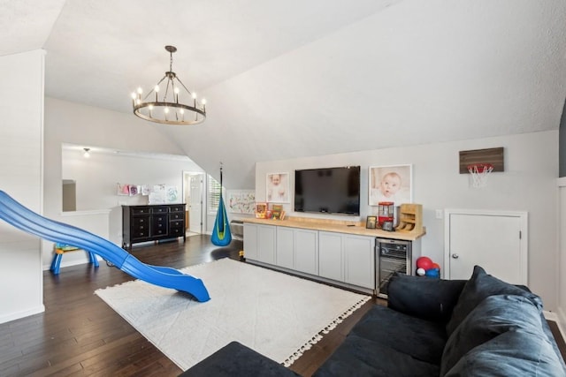 playroom featuring an inviting chandelier, wine cooler, lofted ceiling, baseboards, and dark wood-type flooring