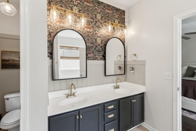 full bath featuring a sink, an accent wall, wallpapered walls, and double vanity