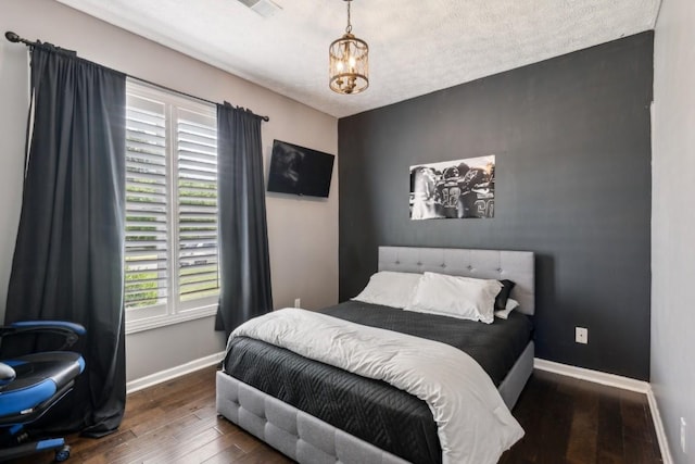 bedroom with baseboards, an accent wall, and hardwood / wood-style floors