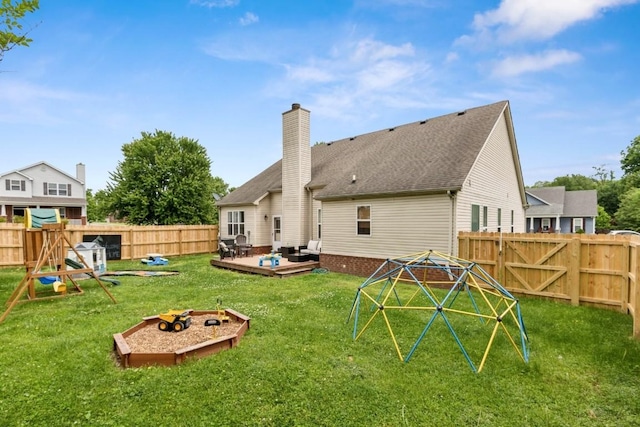 back of house featuring a fenced backyard, a yard, and a fire pit
