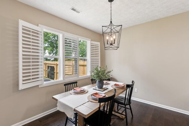 dining room featuring a textured ceiling, visible vents, baseboards, dark wood-style floors, and a chandelier