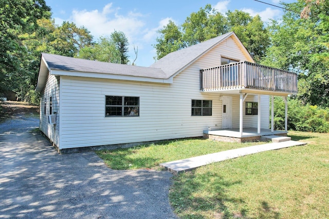 rear view of house with a balcony and a yard