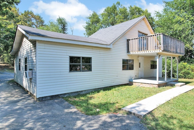 rear view of house featuring a lawn, cooling unit, a balcony, and a patio area