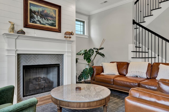living area featuring stairs, visible vents, ornamental molding, and a fireplace