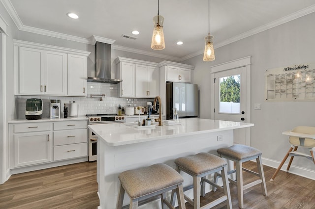 kitchen with wall chimney range hood, visible vents, a sink, freestanding refrigerator, and electric stove