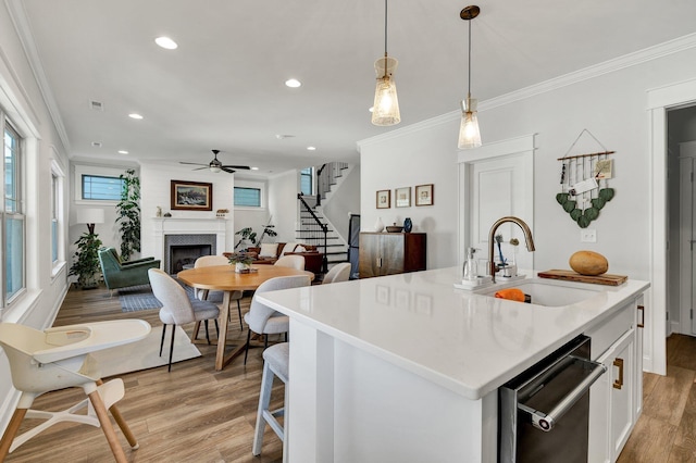 kitchen featuring a sink, crown molding, a fireplace, and a ceiling fan