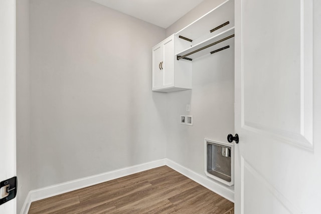 laundry area with baseboards, hookup for a washing machine, cabinet space, and wood finished floors