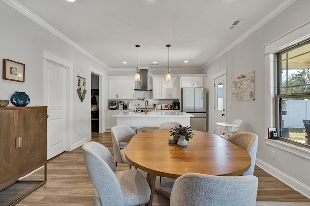 dining room featuring recessed lighting, baseboards, light wood-type flooring, visible vents, and ornamental molding