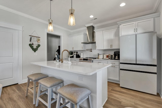 kitchen featuring a breakfast bar, stainless steel fridge, wall chimney exhaust hood, light wood-type flooring, and tasteful backsplash