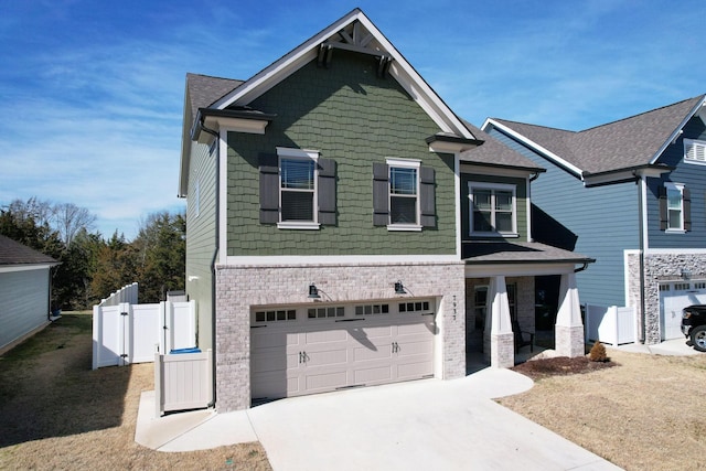 craftsman inspired home with fence, brick siding, a gate, an attached garage, and driveway