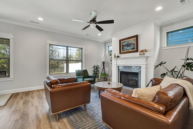 living area with visible vents, a tiled fireplace, wood finished floors, and plenty of natural light