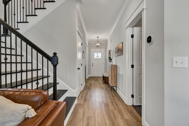 entryway featuring crown molding, visible vents, wood finished floors, baseboards, and stairway