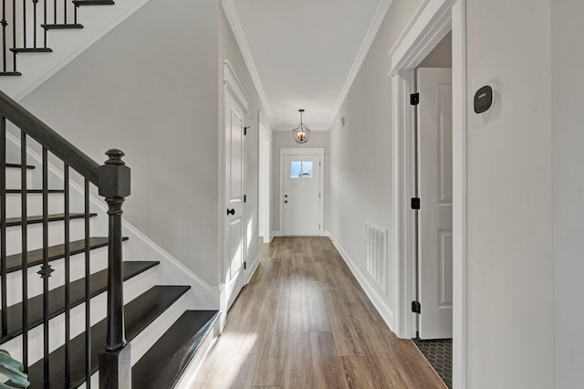 entryway featuring stairs, crown molding, visible vents, and wood finished floors