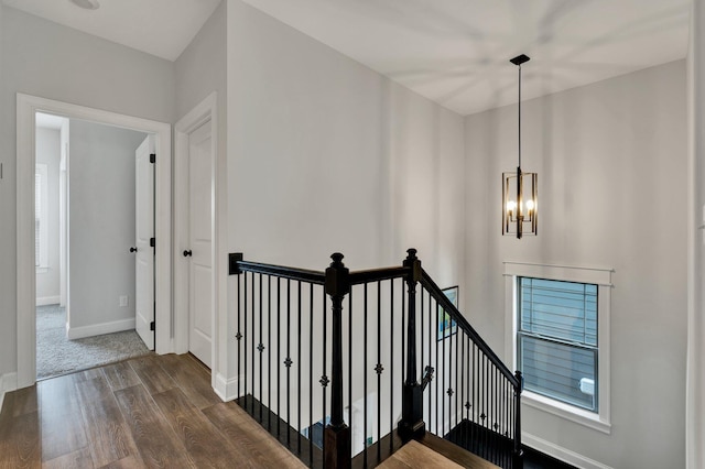 staircase featuring an inviting chandelier, baseboards, and wood finished floors