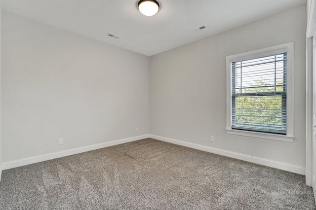 carpeted spare room featuring visible vents and baseboards