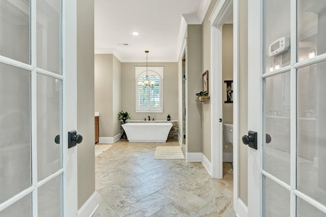 bathroom with toilet, french doors, baseboards, ornamental molding, and a soaking tub