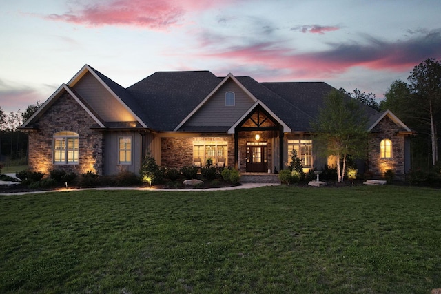 craftsman-style house with a yard and stone siding