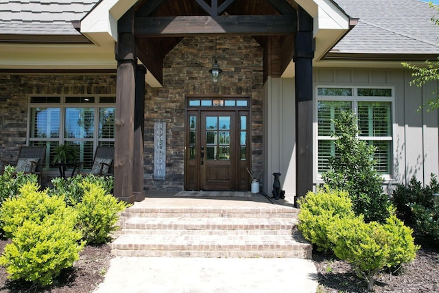 property entrance with covered porch, board and batten siding, a shingled roof, and stone siding