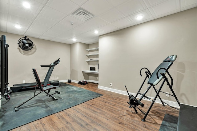exercise room featuring baseboards, recessed lighting, wood finished floors, and visible vents