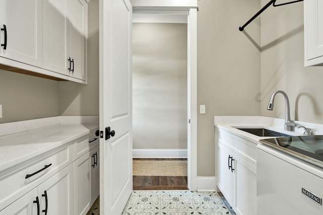 laundry room with a sink, baseboards, and cabinet space