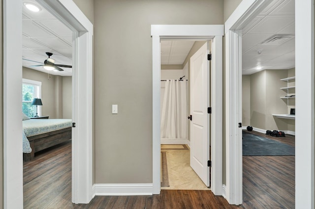 hallway featuring baseboards, visible vents, and dark wood finished floors