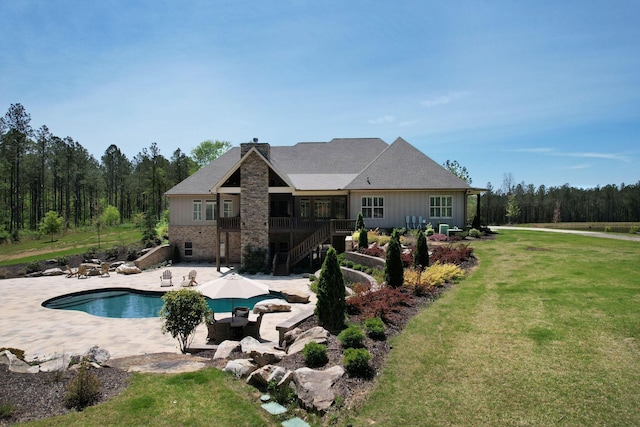 rear view of property featuring brick siding, stairway, a chimney, a patio area, and a yard