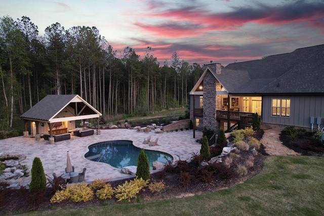 pool featuring a wooden deck, a patio, an outbuilding, and an exterior structure