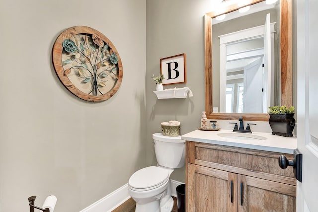 bathroom with toilet, baseboards, and vanity