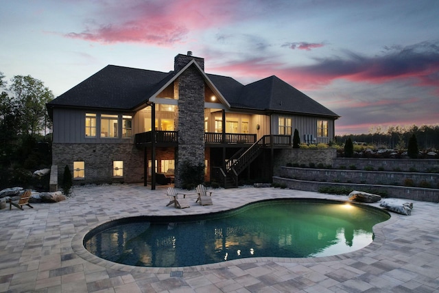 pool at dusk featuring a patio area, an outdoor pool, stairway, and a deck