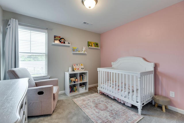 bedroom featuring visible vents, baseboards, a nursery area, and light carpet