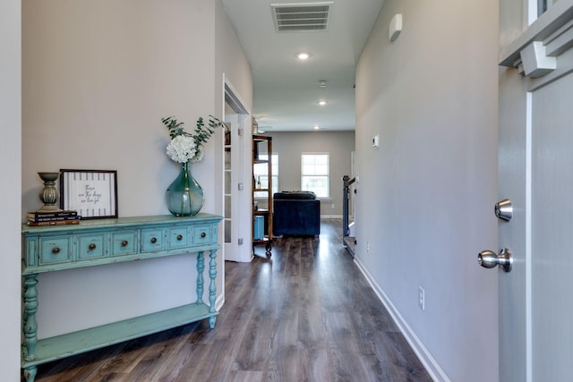 hallway featuring dark wood-style flooring, baseboards, visible vents, and recessed lighting
