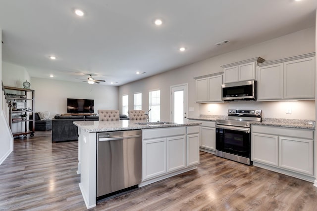 kitchen featuring ceiling fan, visible vents, a sink, stainless steel appliances, and an island with sink