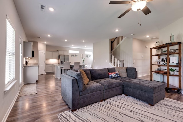 living area featuring baseboards, visible vents, wood finished floors, and stairway