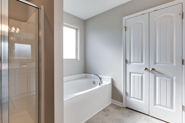 bathroom featuring baseboards, a shower stall, and a bath
